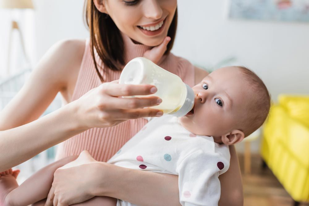 madre alimentando a bebé con leches de crecimiento