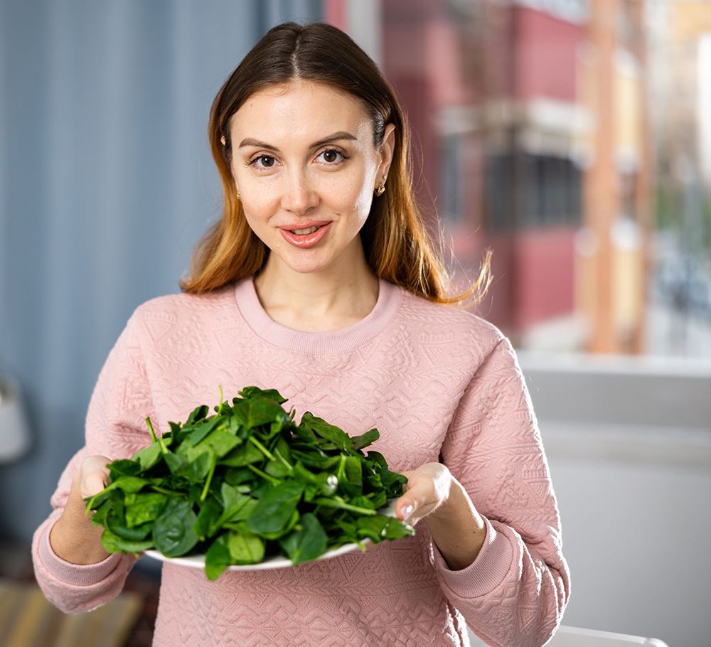 Smiling girl eating green salad at home